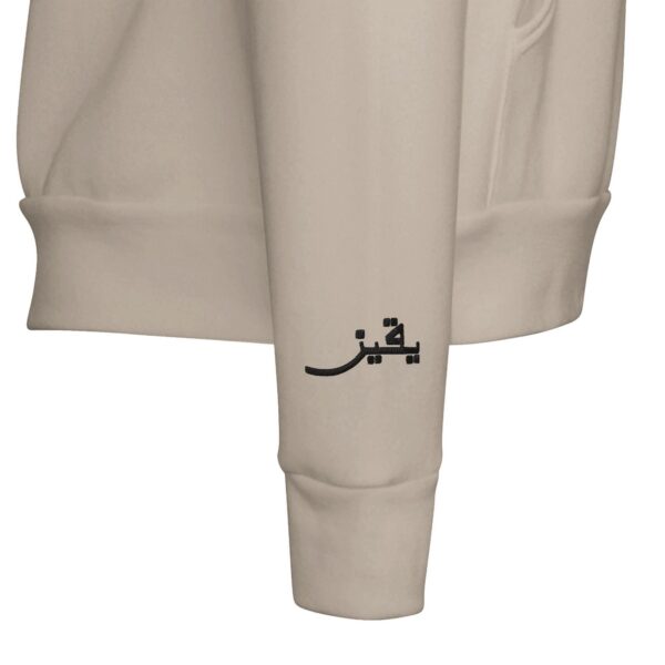 Close-up of embroidered Arabic script on a dark pullover hoodie by Artkins