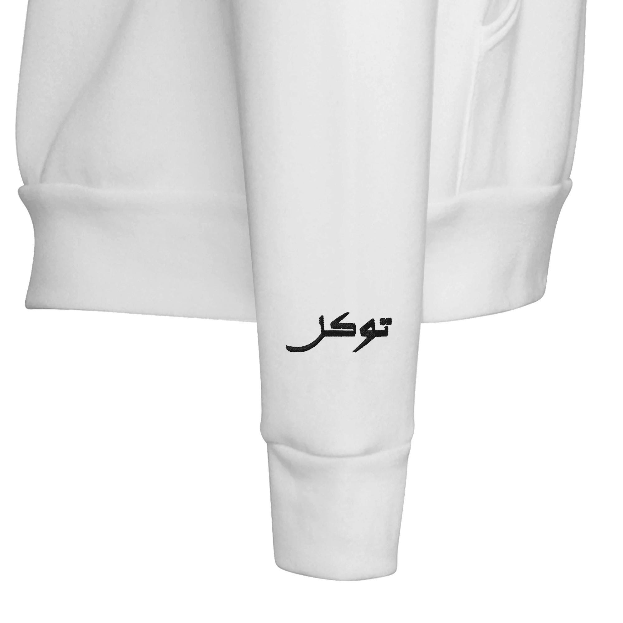 Close-up of embroidered tawakkal lettering in Arabic on a pullover hoodie